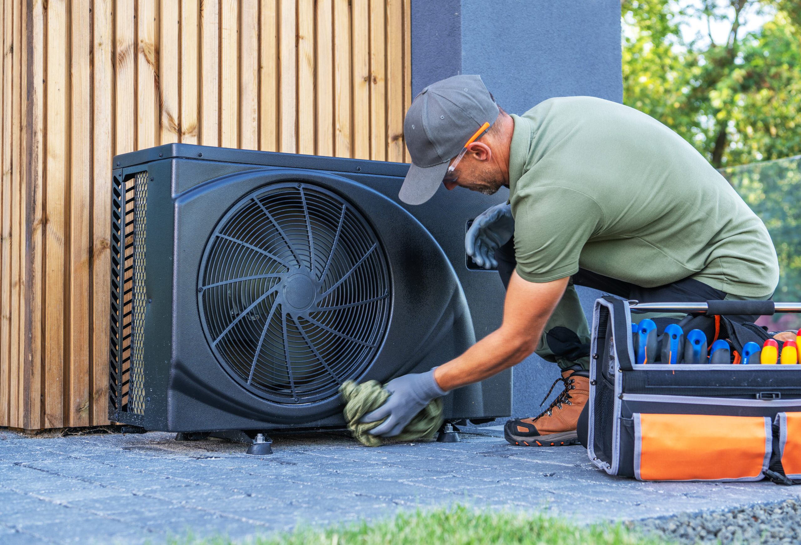 Techniker bei der Reinigung und Wartung einer modernen Wärmepumpe im Außenbereich