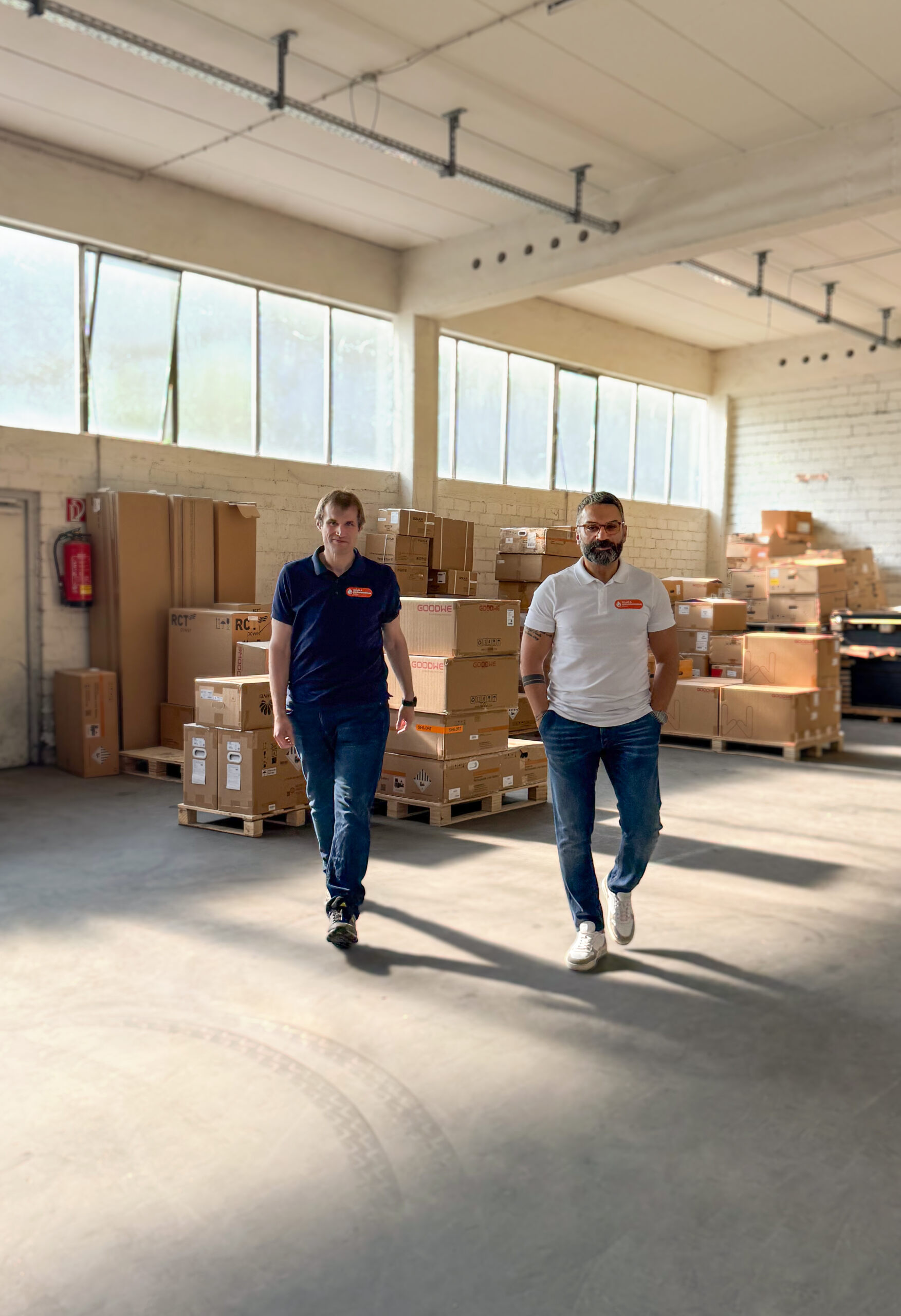 Die beiden Gründer von Heizungsenergie gehen gemeinsam durch die firmeneigene Lagerhalle